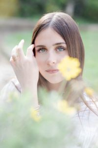 Portrait photo Luana en extérieur dans les champs au printemps fleur - focus sur ses yeux bleus